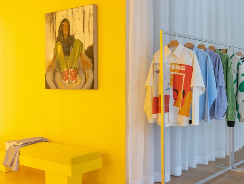 Phòng thử đồ màu vàng với thanh treo quần áo ở bên phải