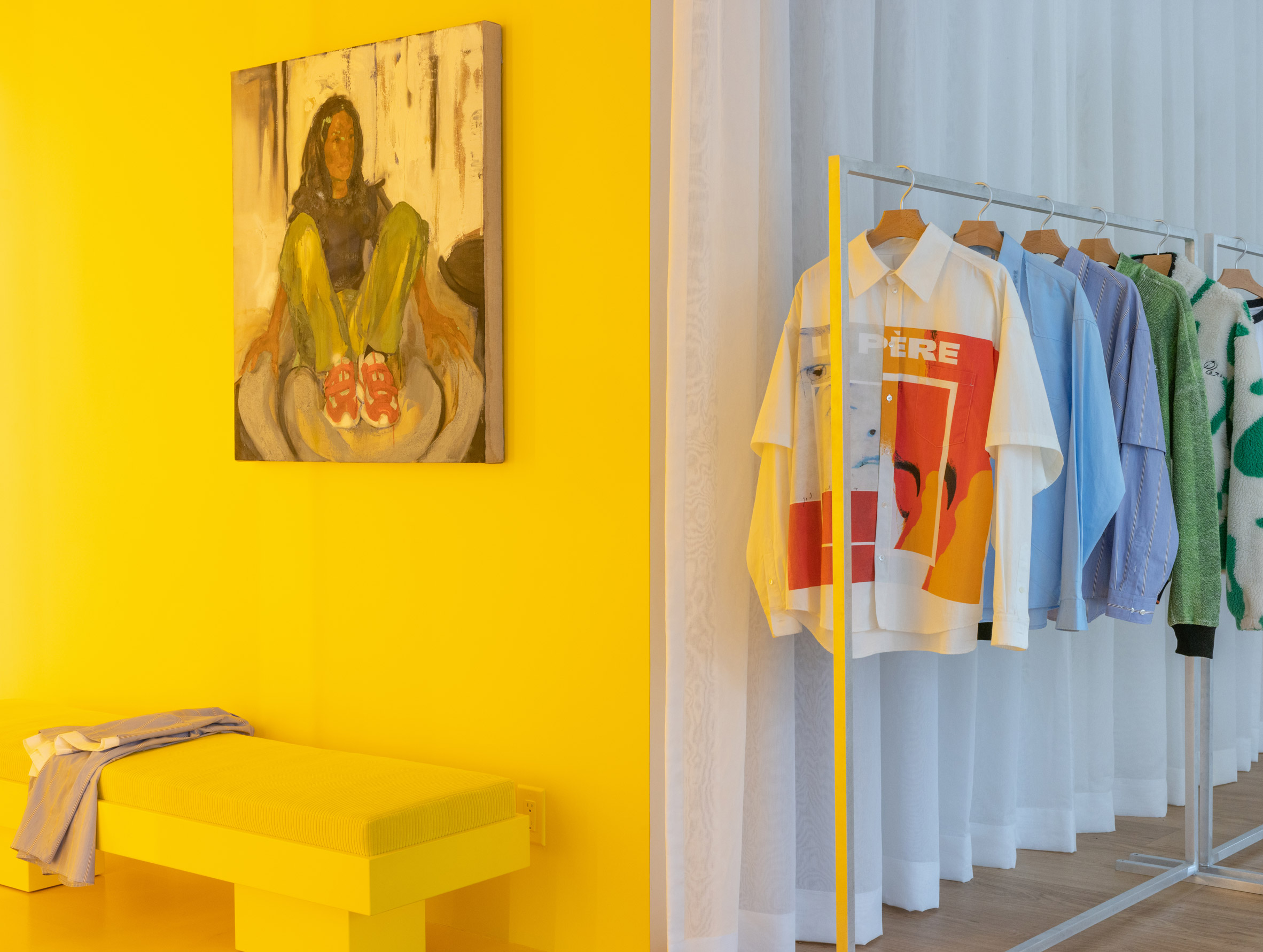 Yellow fitting room with a rail of clothing to the right