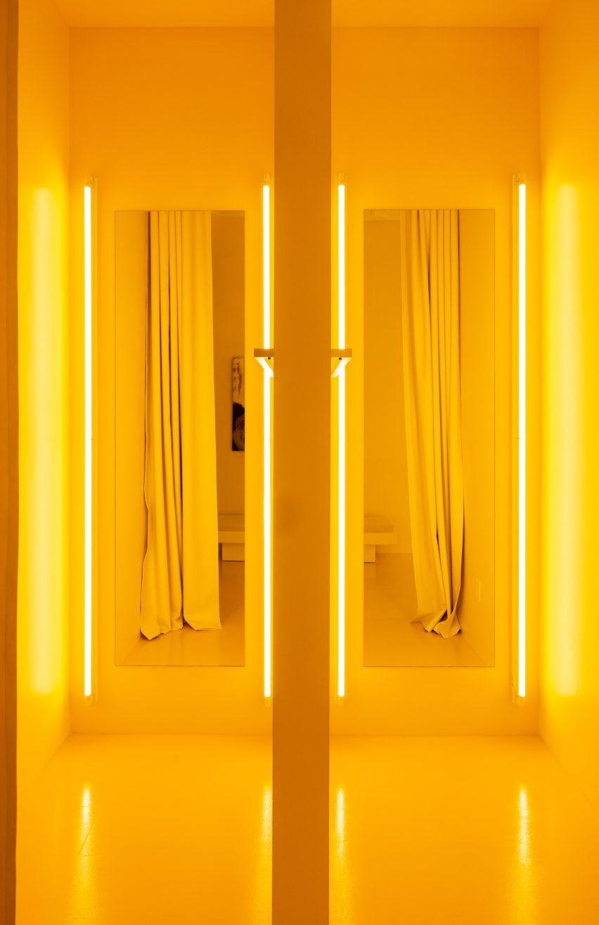 Pair of yellow fitting rooms with tube lights either side of the mirrors