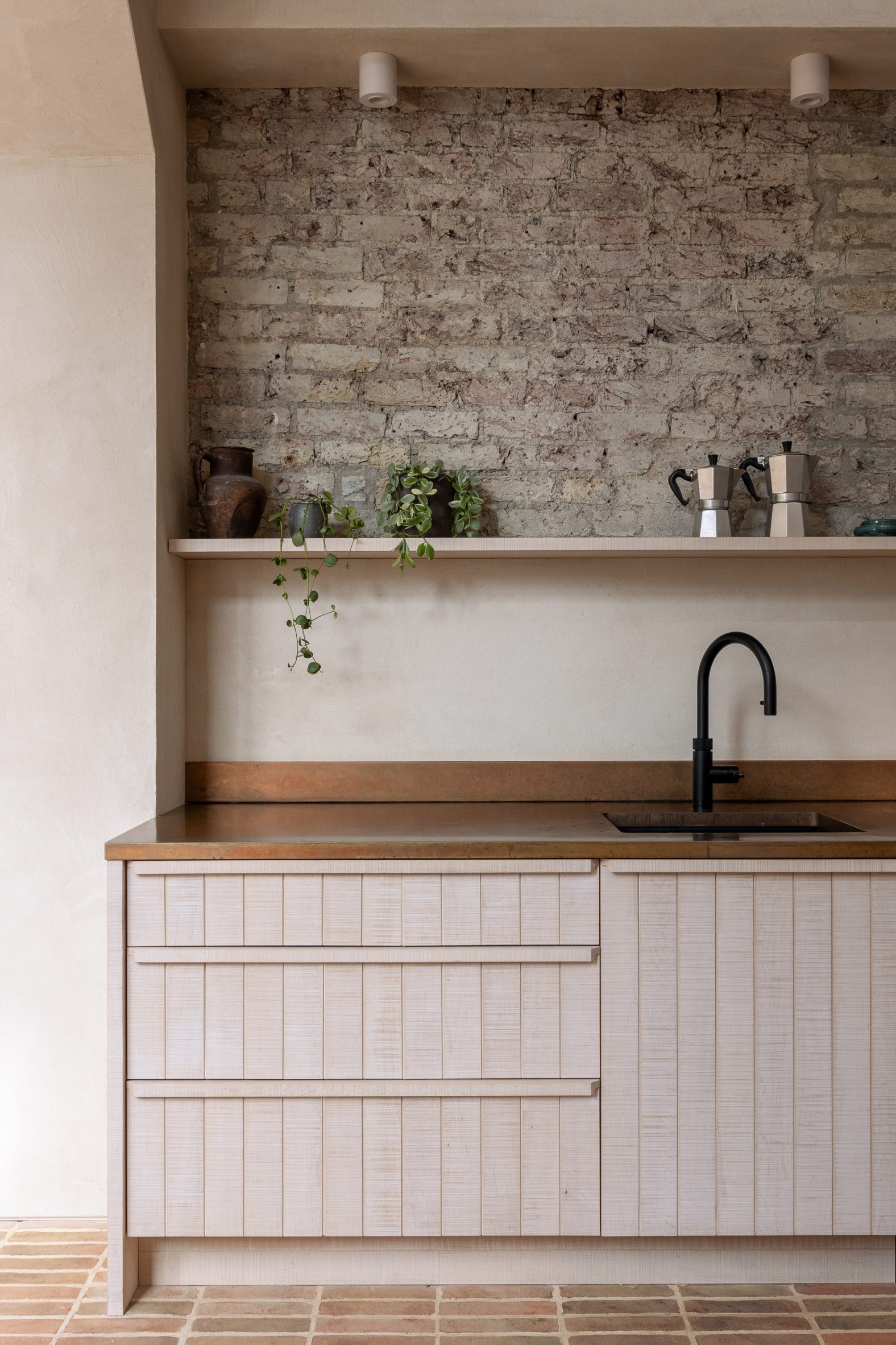 Wooden kitchen cabinetry set against brickwork wall