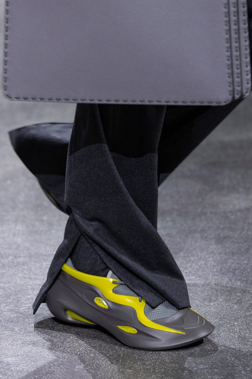 Close-up of model wearing grey-and-yellow trainers