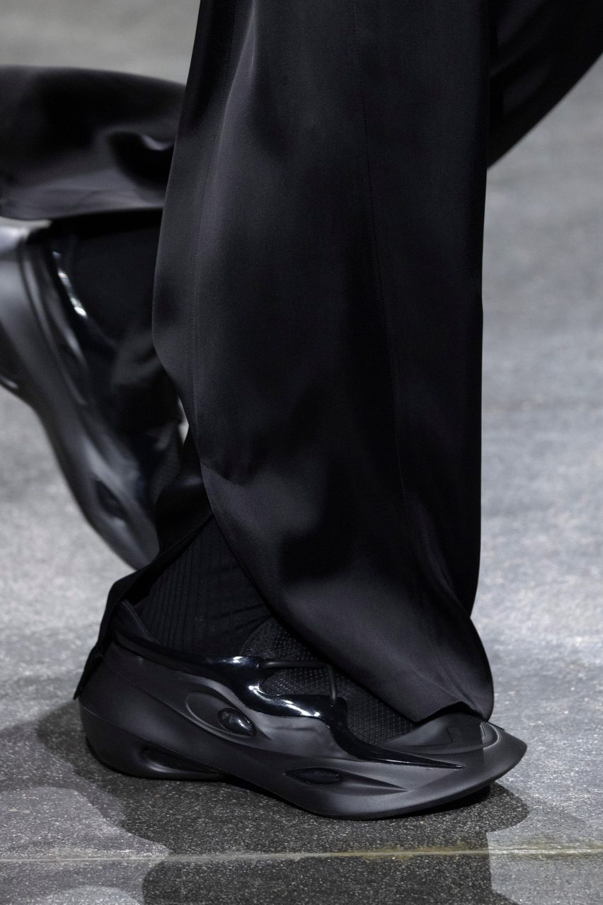 Close-up of model wearing black trainers on a runway