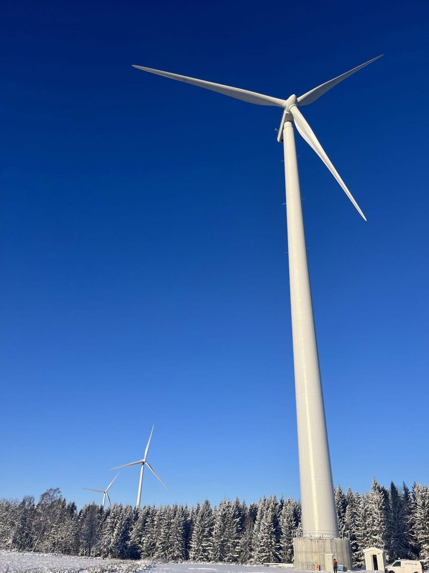 Portrait photograph of a tall wind turbine against a bright blue sky
