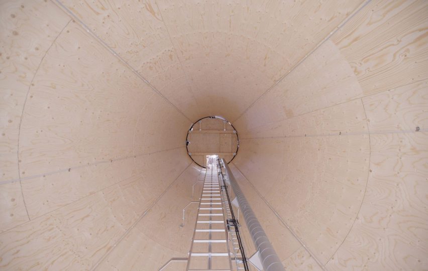 Photo of the inside of a large timber cylinder, with a ladder going up the middle