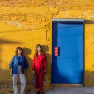 two people standing in front of a yellow wall