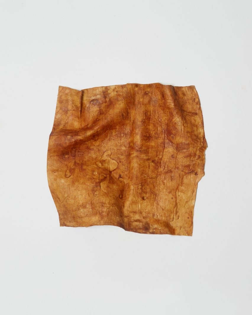 A small square piece of leather-like material, in a mottled hue of caramel brown 