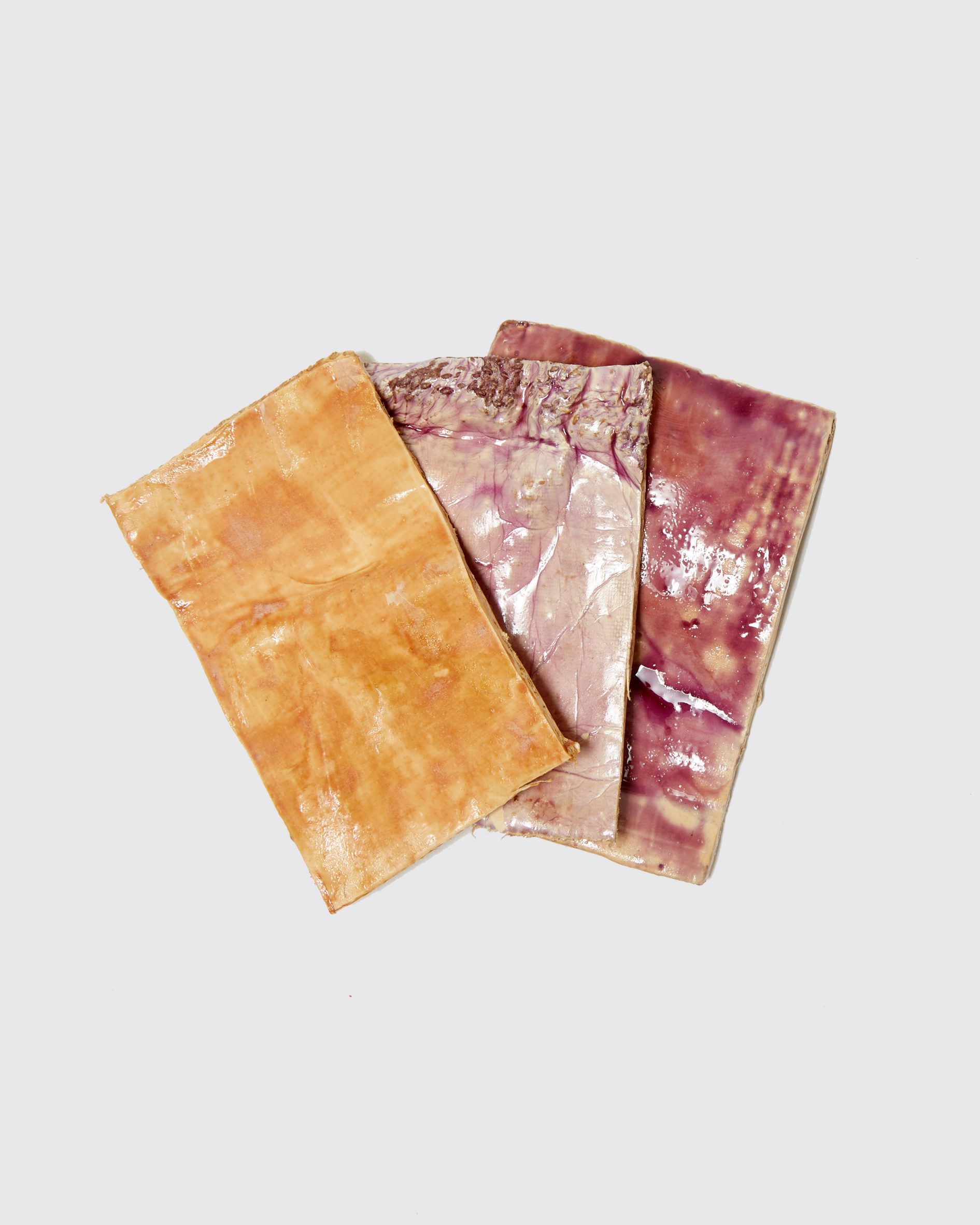 Photo of swatches of mycelium dyed in different shades of tan, pale violet and mulberry