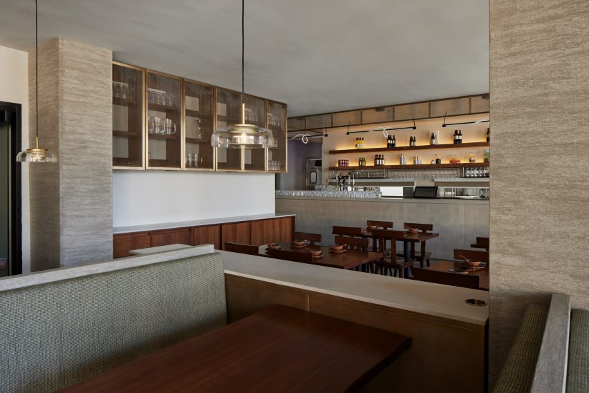 A free-seating area beside a bar featuring walnut furniture and floating metal cabinets