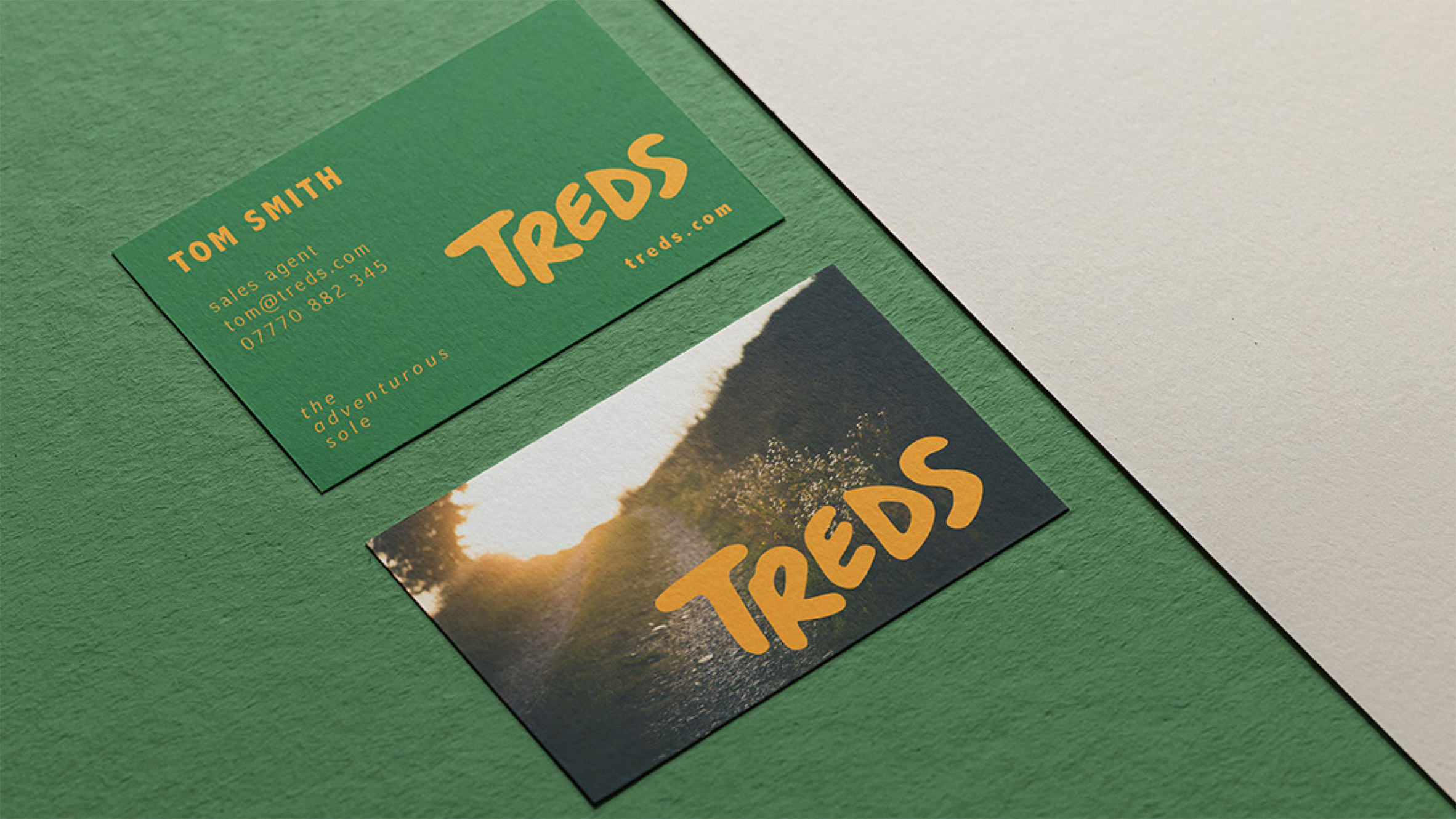 Business cards with green and yellow branding for outdoor footwear
