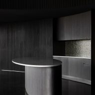 Kitchen with a black rounded island and black timber walls