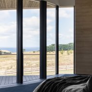 Bedroom with floor-to-ceiling windows overlooking a grassy landscape