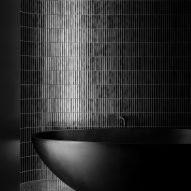 Black tiled bathroom with a black bathtub