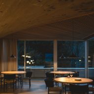 Dining tables beneath a concrete paraboloid and slatted wooden ceiling panels inside a brutalist restaurant in Spain by Zooco Estudio