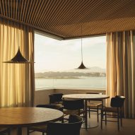 Dining tables overlooking views of the bay from a frameless corner window inside a brutalist restaurant in Spain by Zooco Estudio