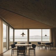 Dining tables overlooking views of the bay inside a brutalist restaurant in Spain by Zooco Estudio