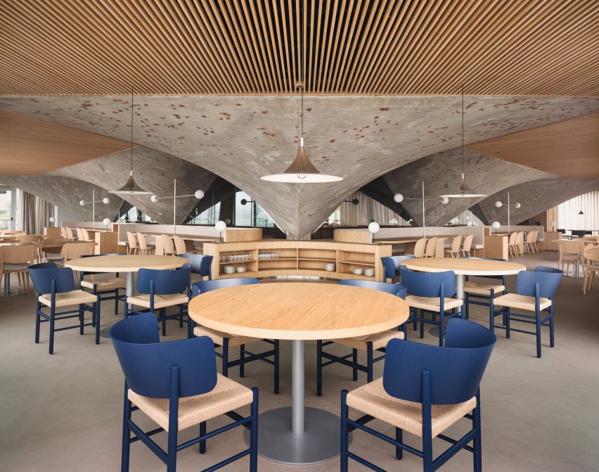 Timber ceiling panels and concrete paraboloids inside a brutalist restaurant