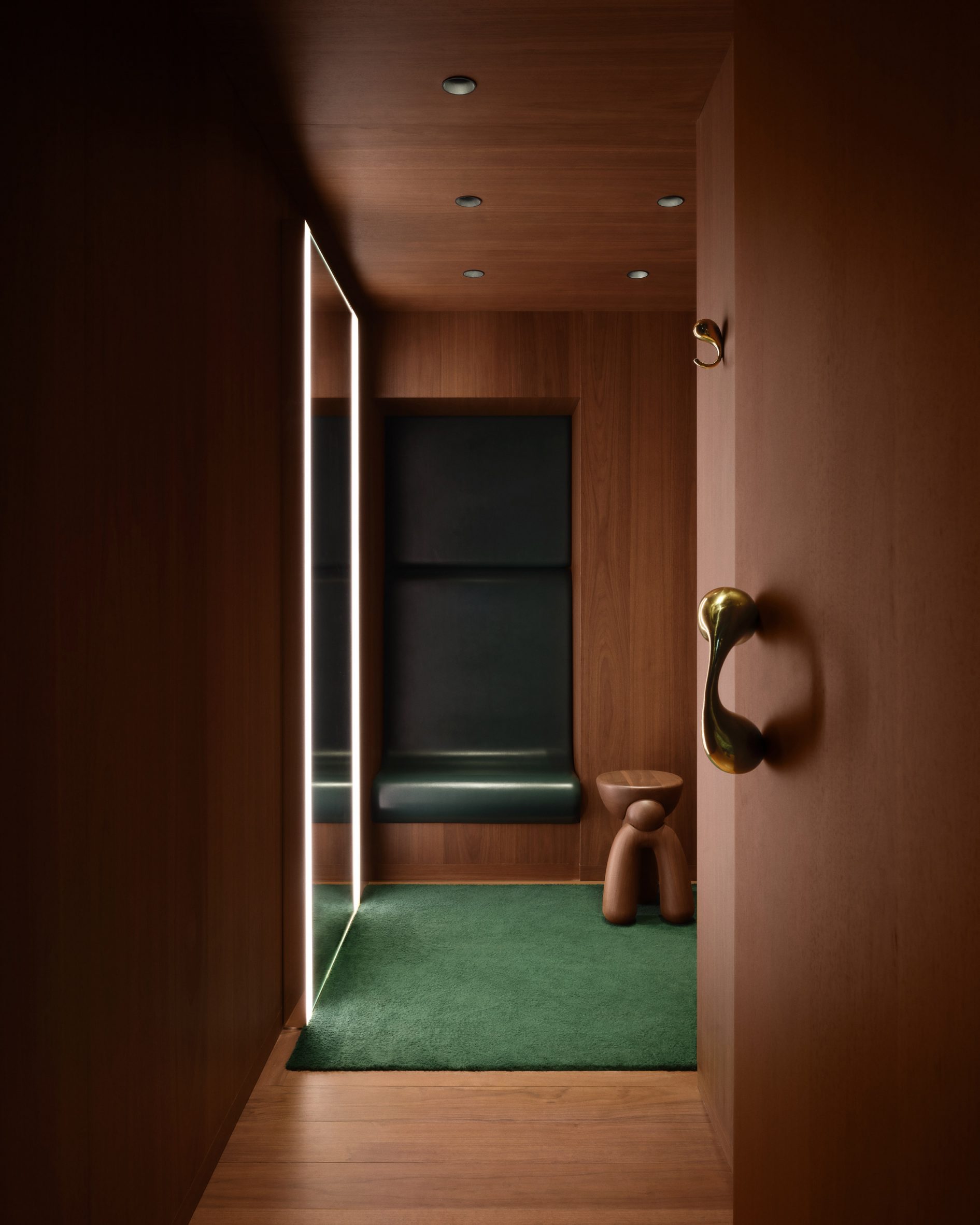 Fitting room lined in walnut with a green leather niche and wool carpet
