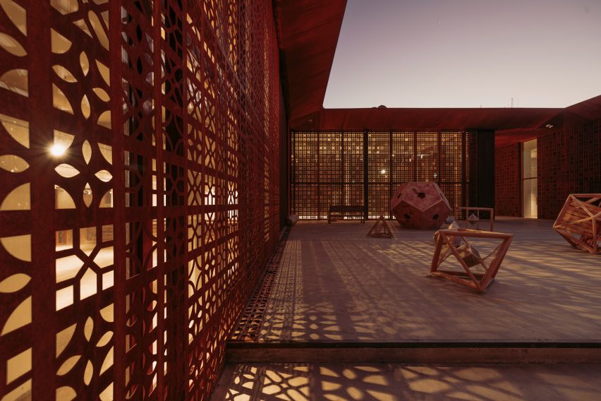Photo of the an internal courtyard filled with sculptures and surrounded by lattice-like weathered steel screens that case shadows on the ground