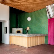A green tile wall surrounding pizza oven