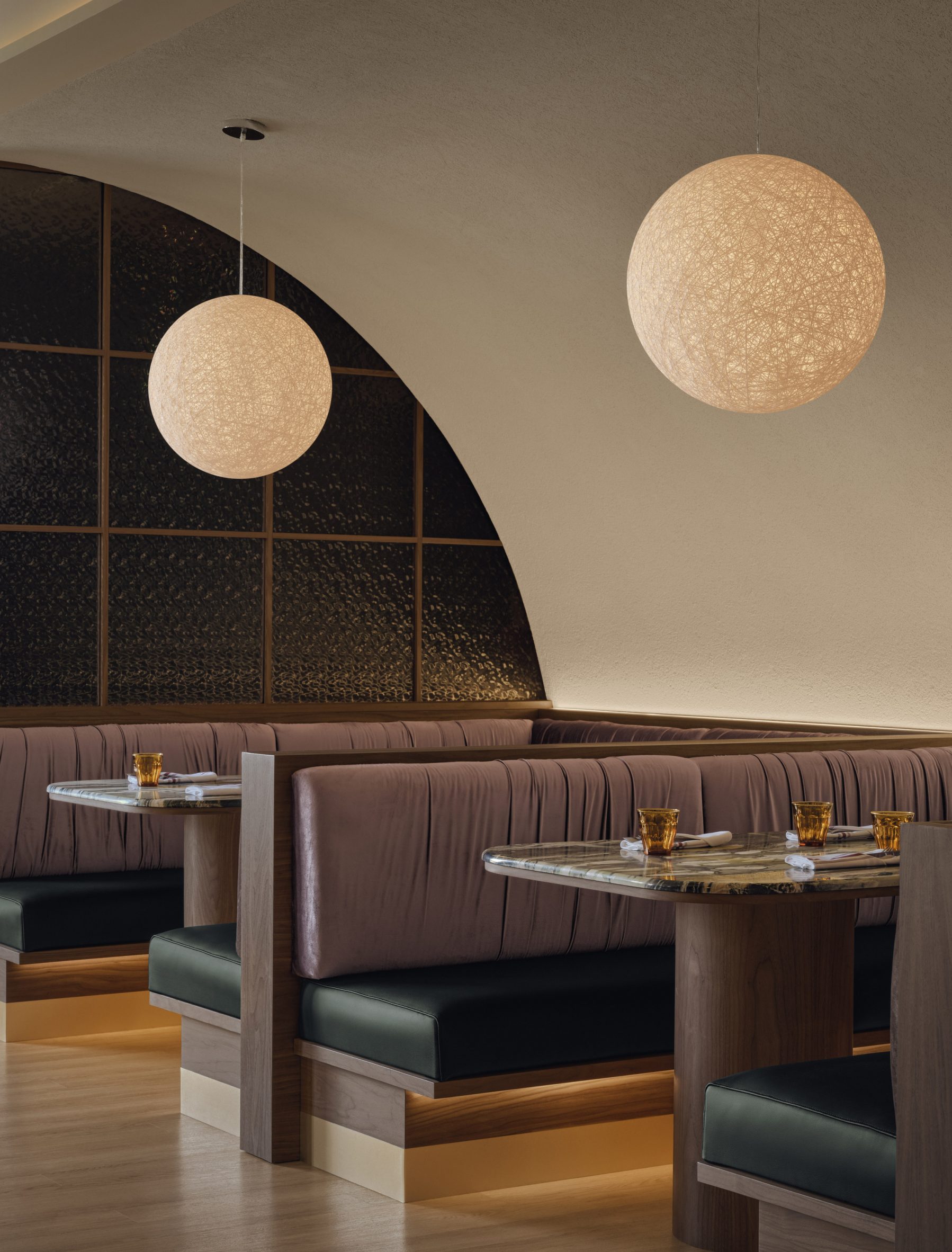 Private booths positioned below an arched ceiling and behind a partition of black hammered glass
