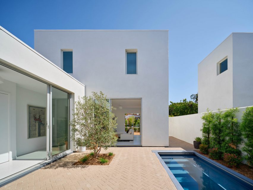 White stucco home with small tree and soaking pool in courtyard