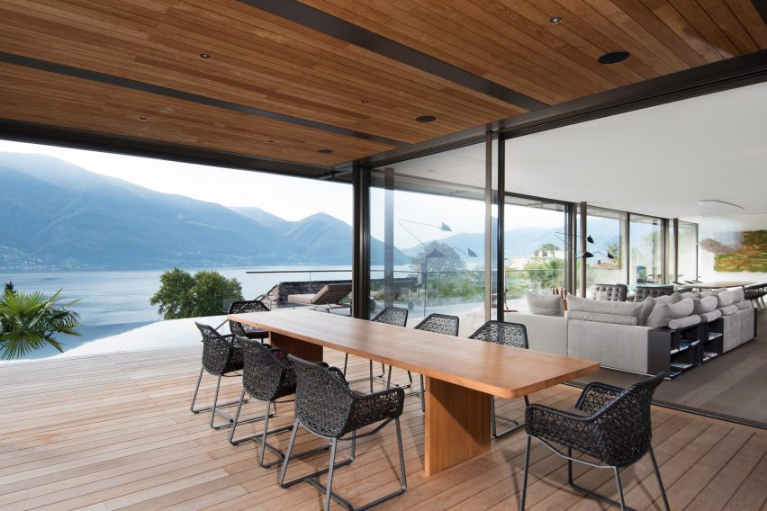 Covered outdoor dining terrace inside a cantilevered house by Küchel Architects in Switzerland