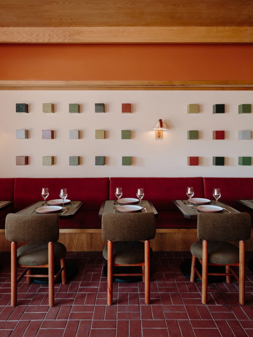 A series of coloured wooden cubes mounted on a wall above banquette seating and dining tables