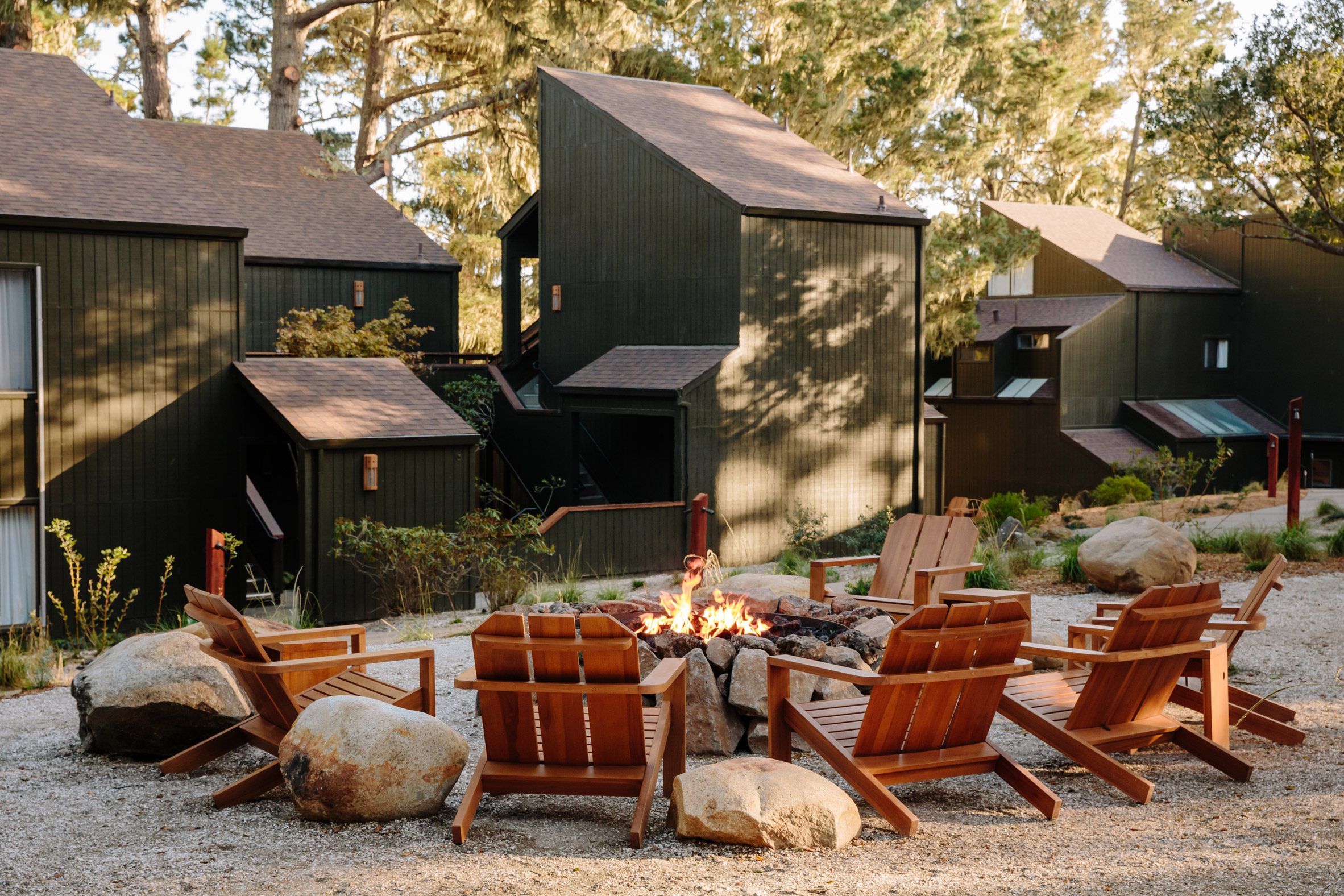 Wooden chairs surrounding a fire pit with blackened wood buildings in the background