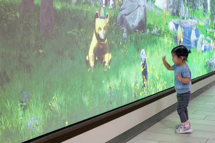 Kid touching a screen with a bear on it