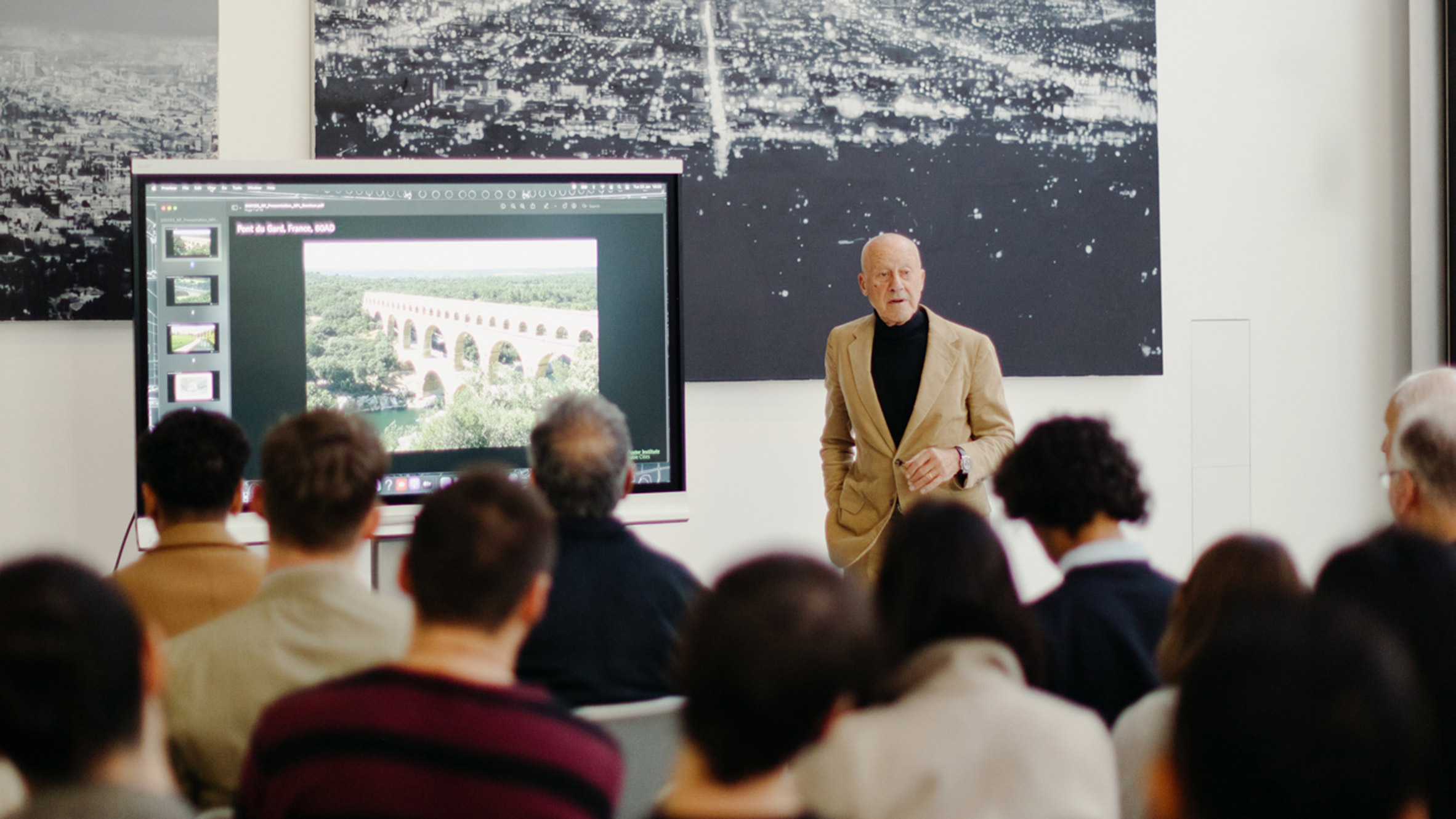 class of students looking at the teacher presenting on a screen