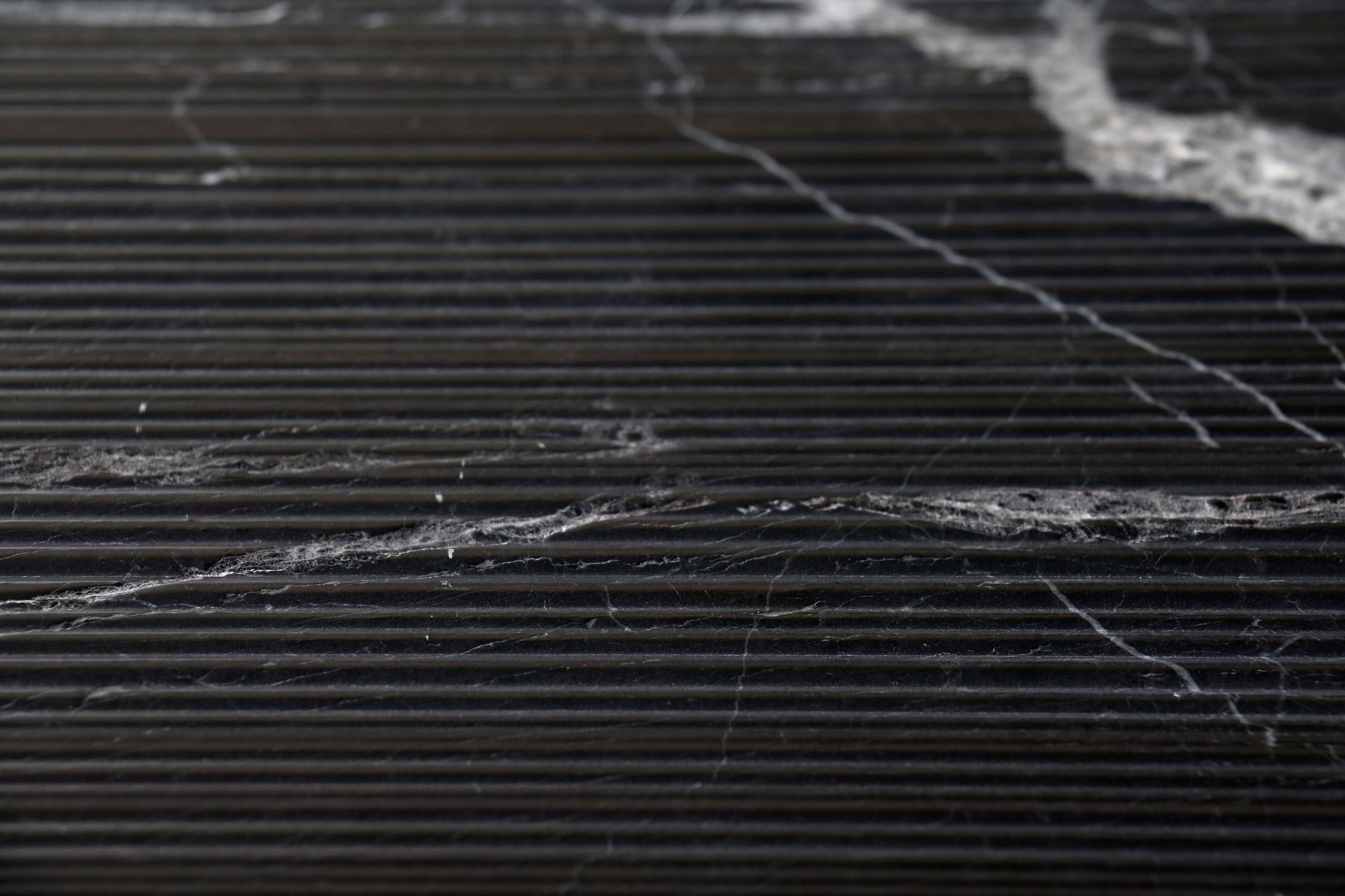 Close-up photo of Antolini's New Marquina black stone with white veining patterned with a Bamboo finish