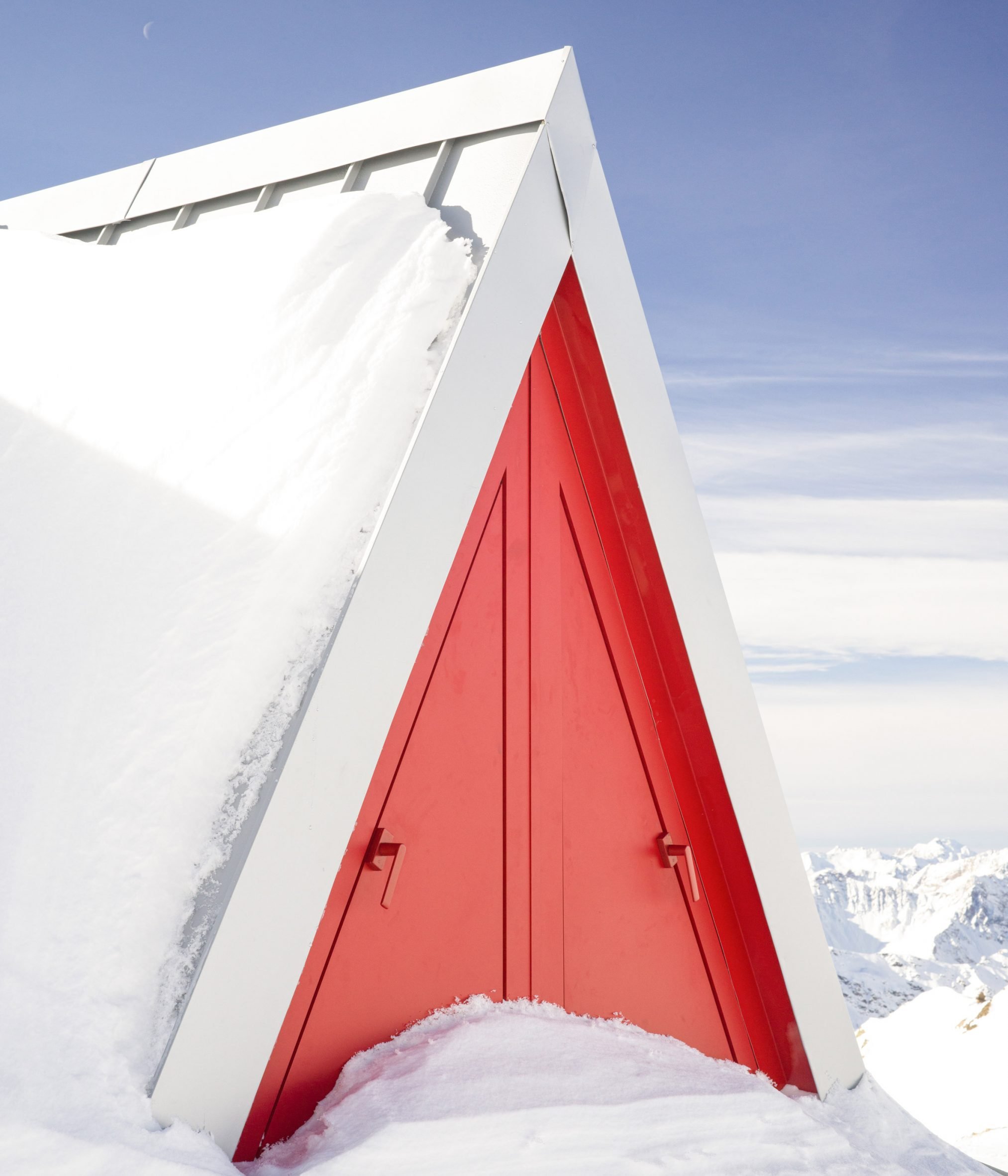 The red triangle door of Pinwheel shelter in the Italian Alps by EX