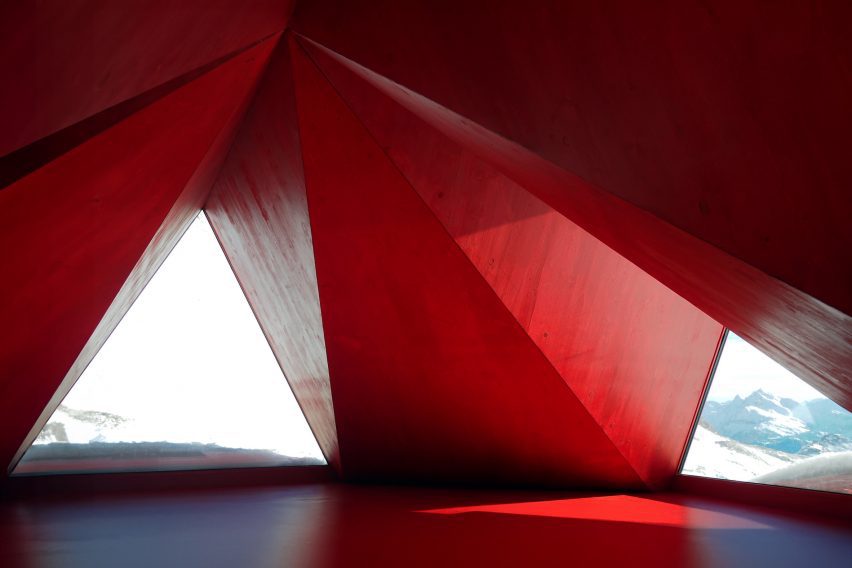 Red angular interior of Pinwheel shelter in the Italian Alps by EX