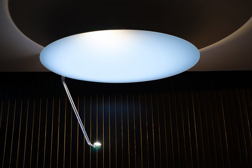 Ceiling light with a metal arm pointed at a reflector panel