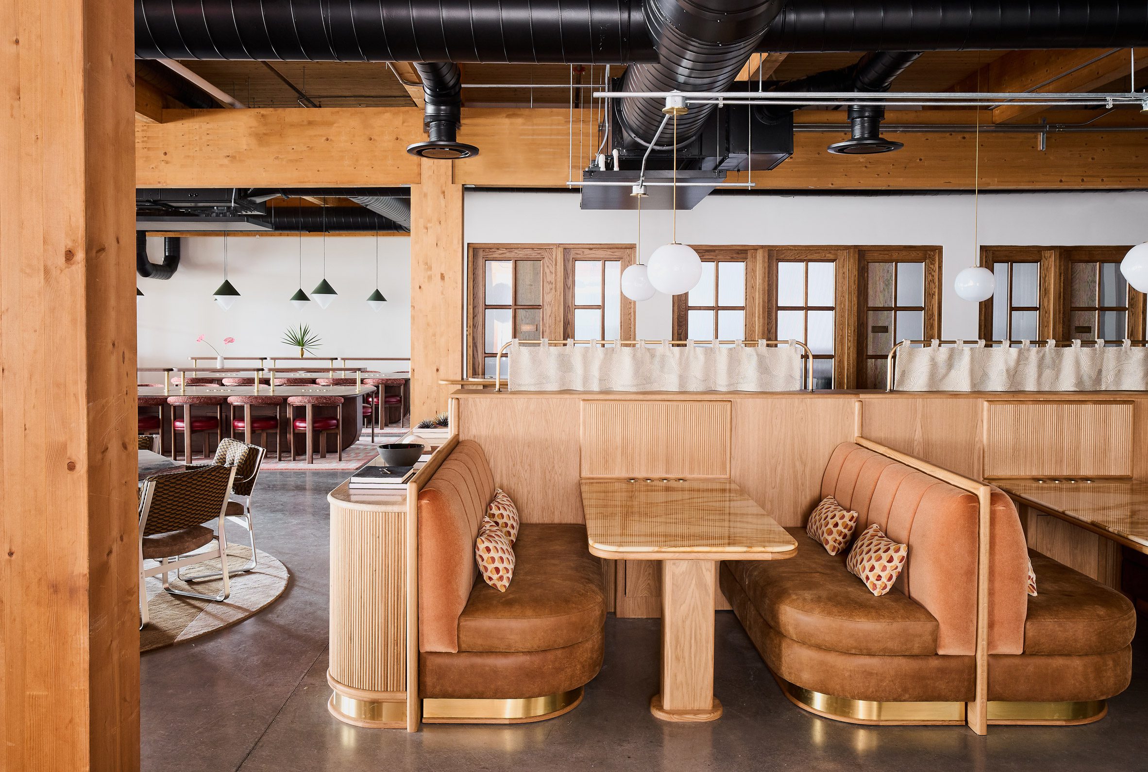 Oak banquettes with velvet upholstery within industrial-style space