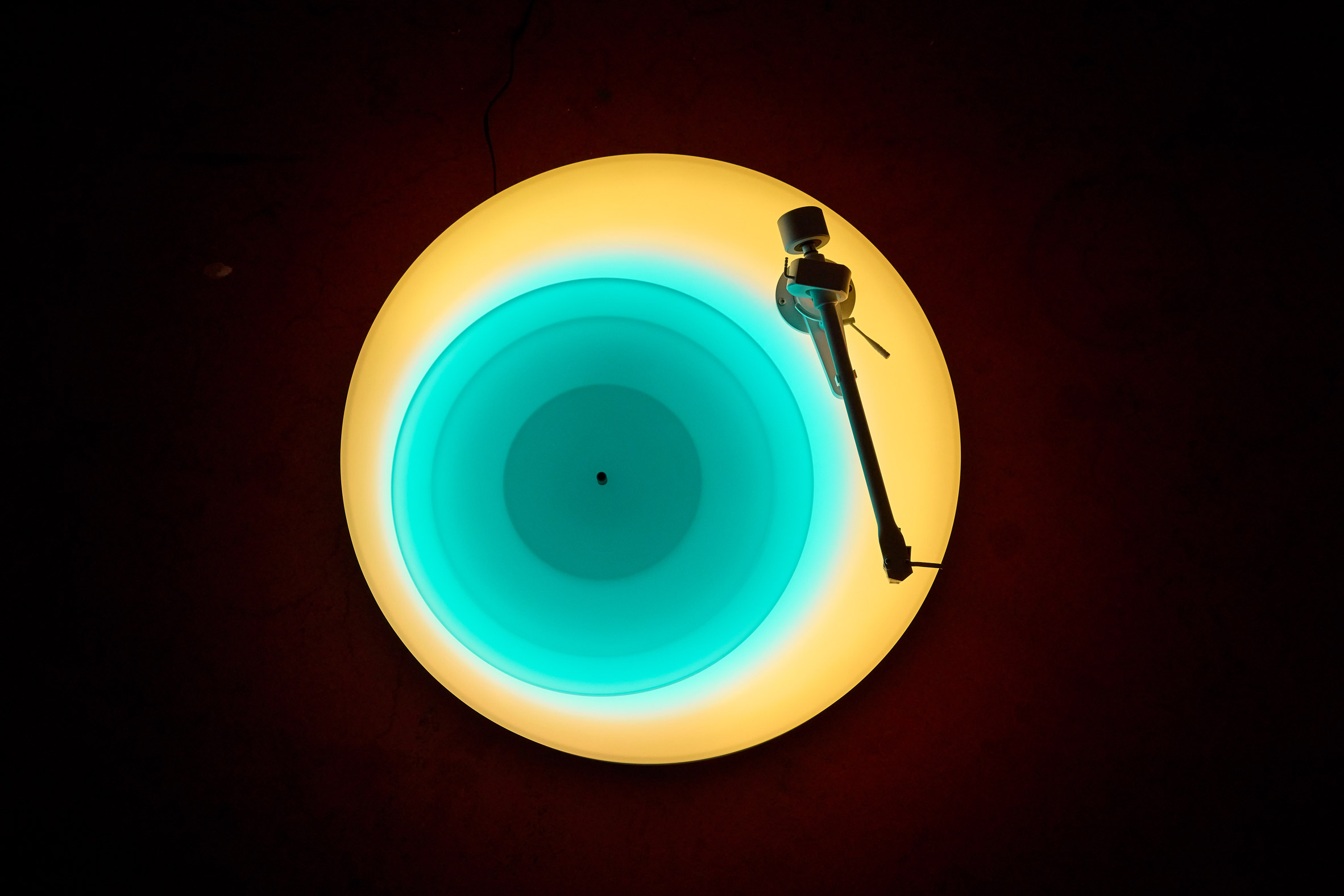 Overhead view of yellow and blue illuminated record player by Brian Eno