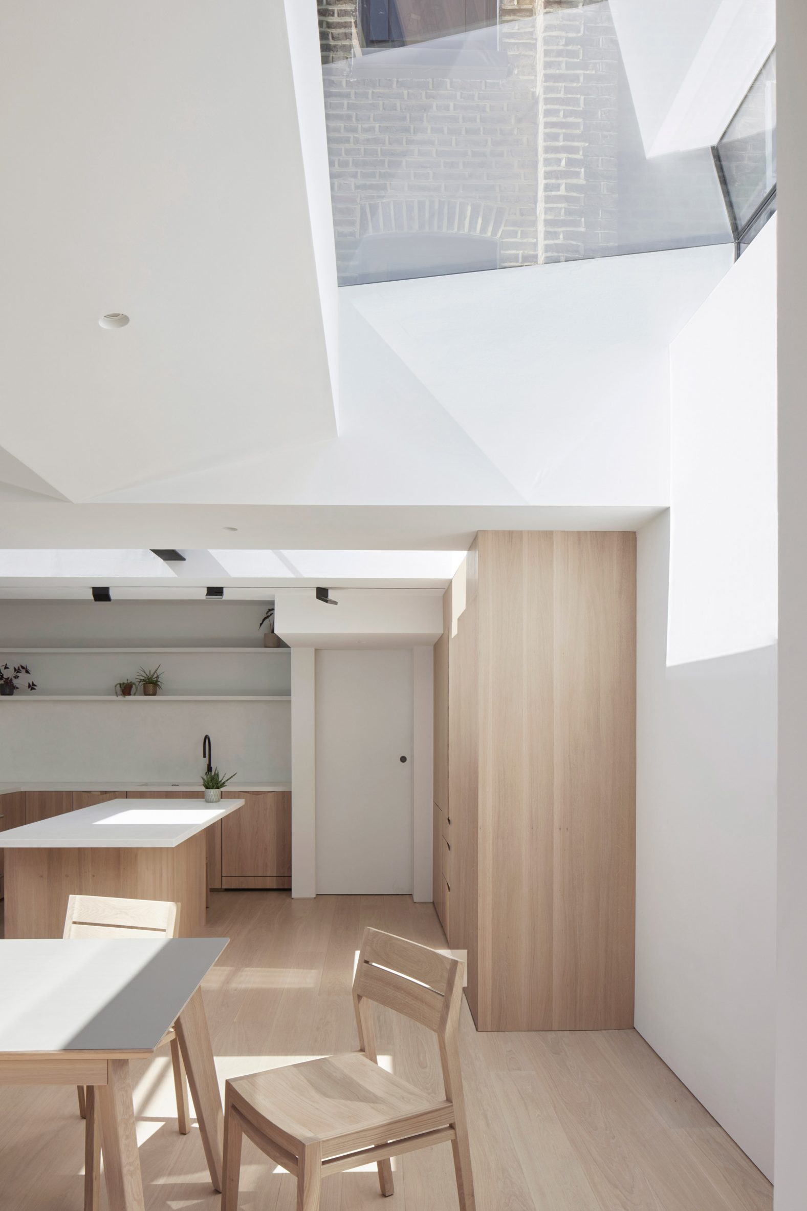 White kitchen and dining room of Butterfly House by The DHaus Company