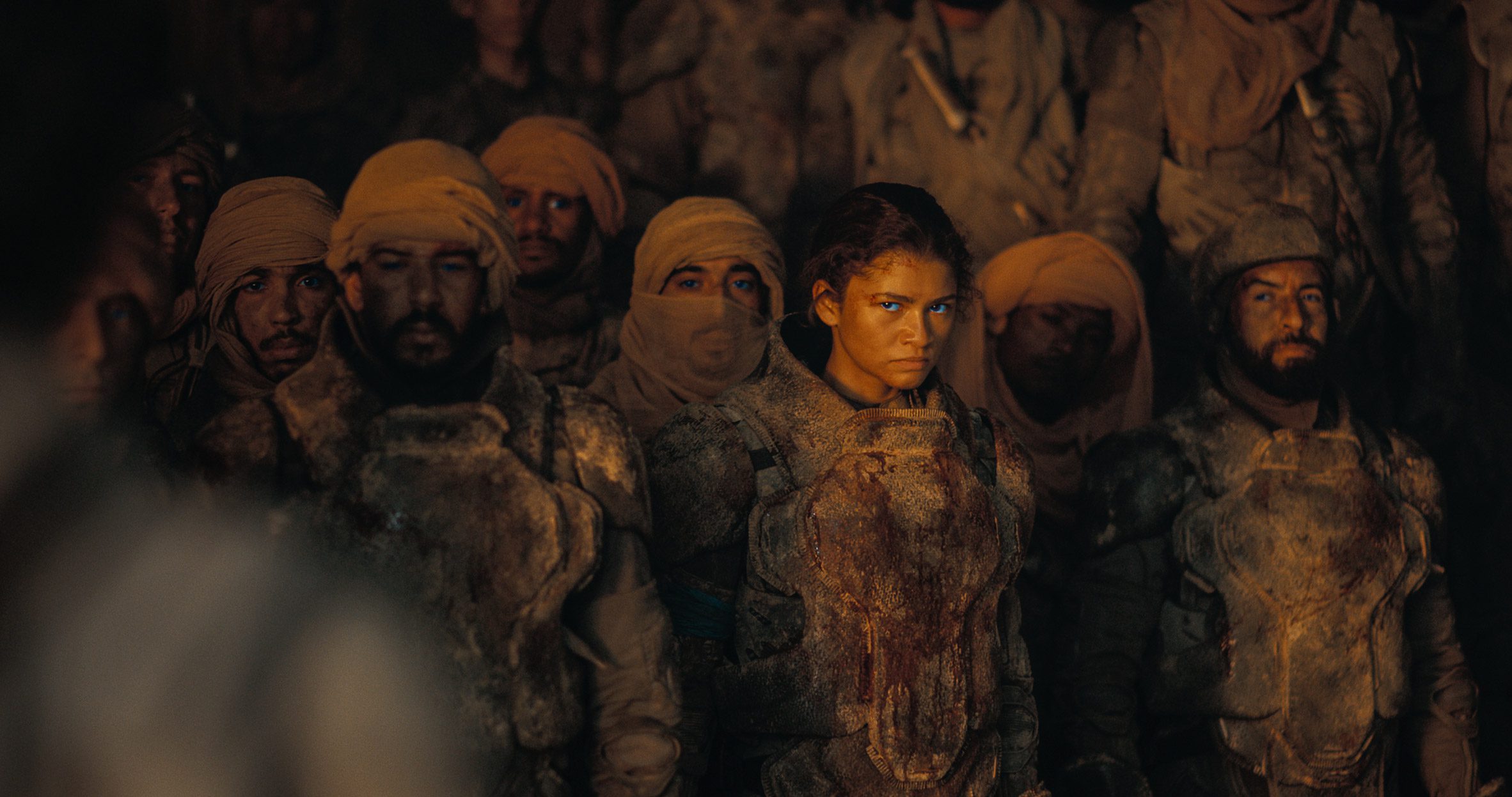 Dune Part Two production photo showing Zendaya as Chani glaring out from within a crowd of Fremen fighters, wearing a mix of headscarves and helmets