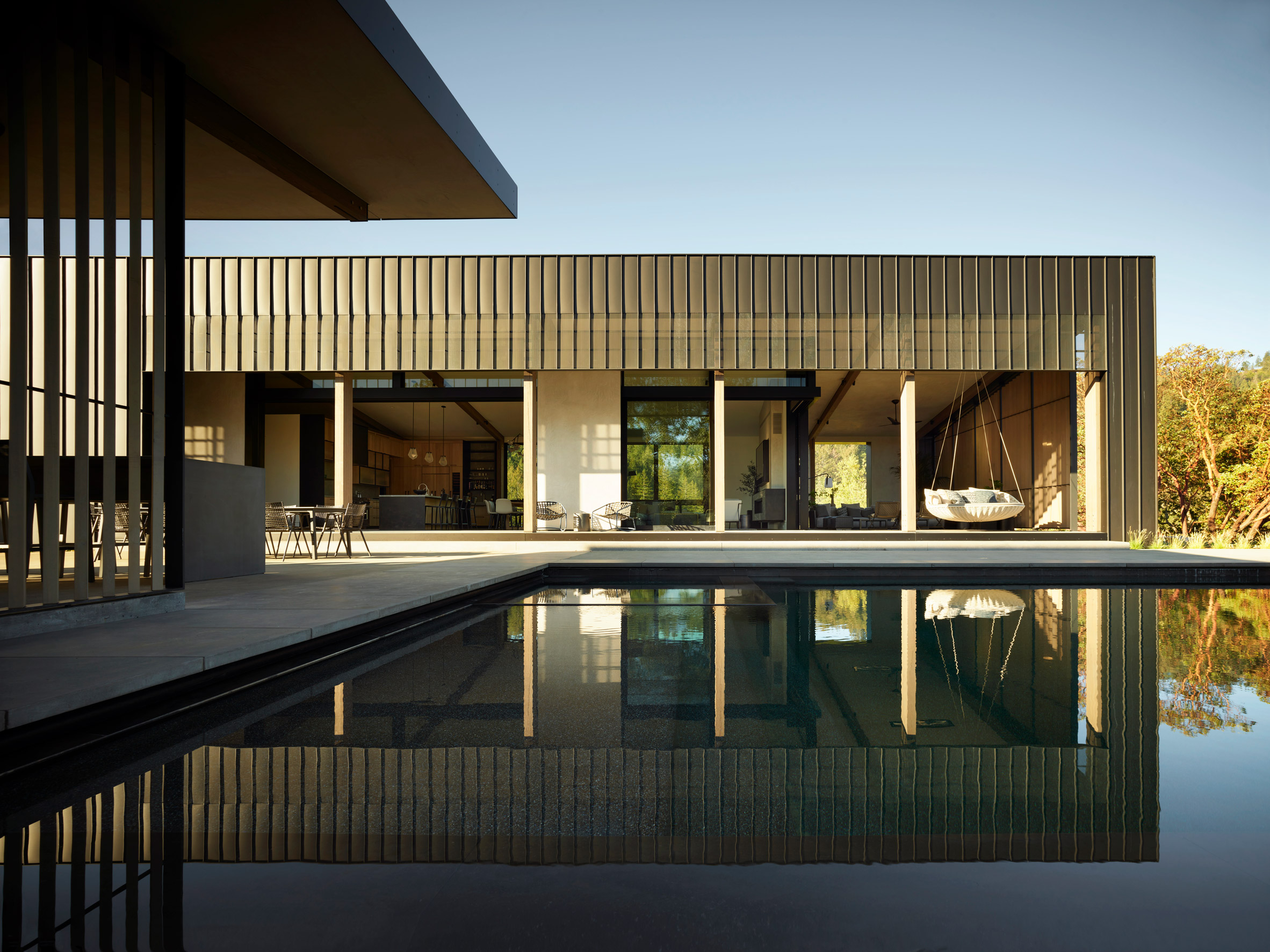 Standing seam rectilinear home overlooking a swimming pool