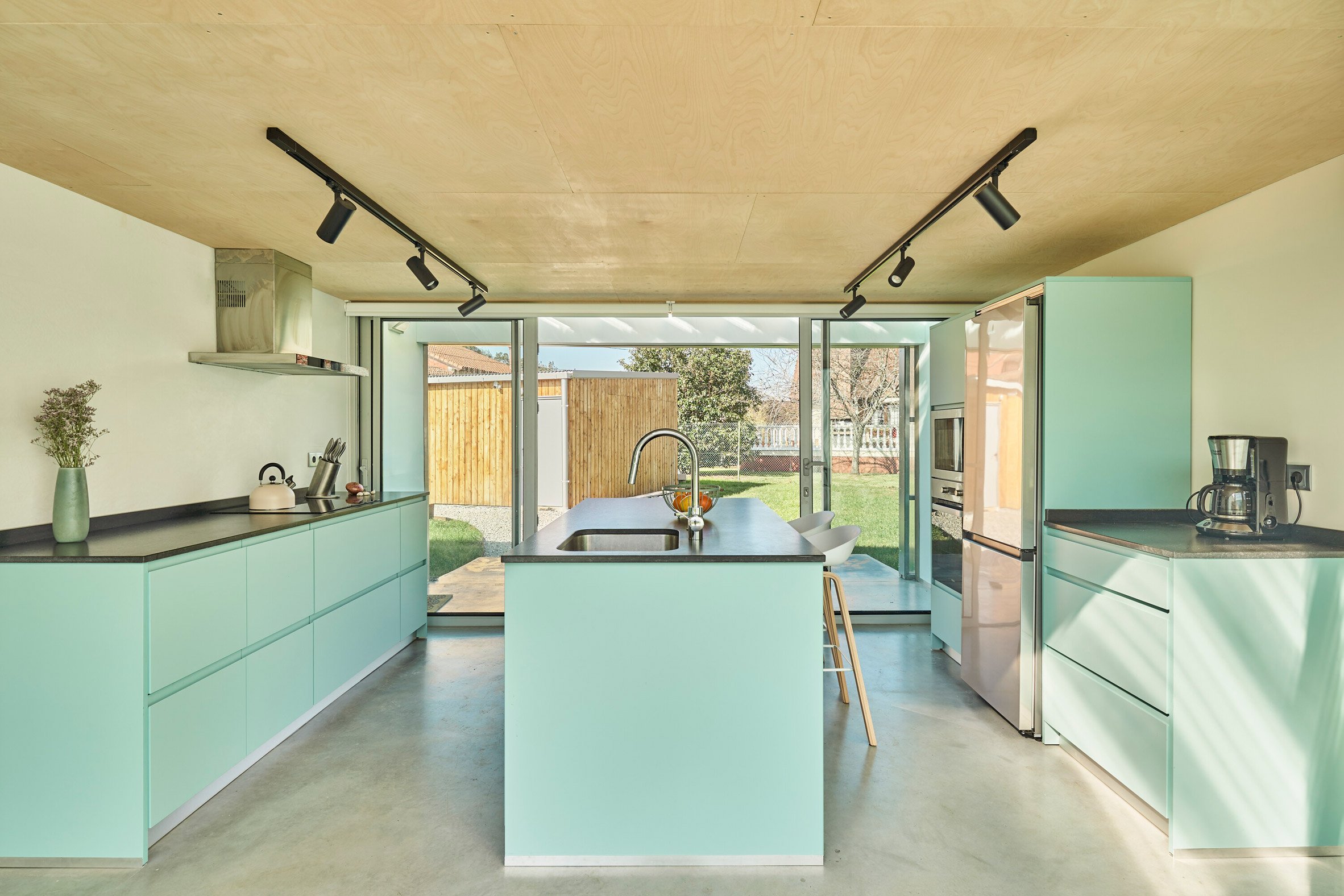 Teal kitchen in The Cork and Wood House by Gurea Arquitectura Cooperativa in Spain