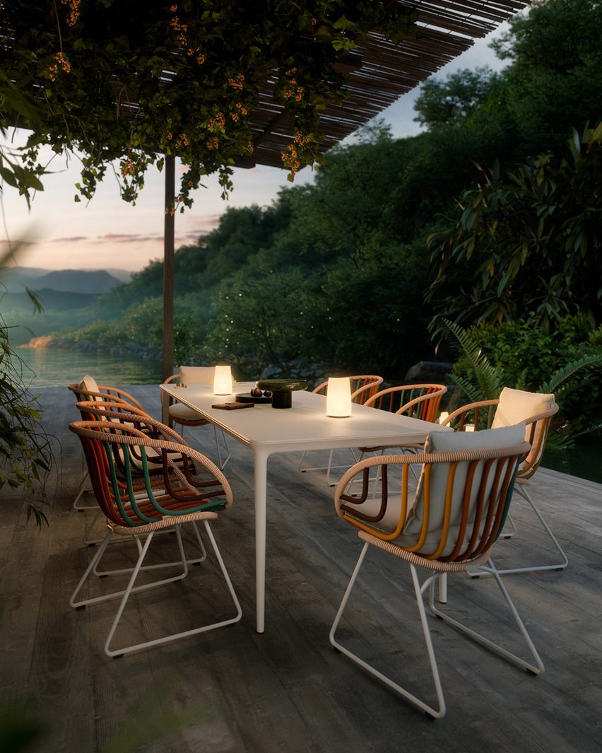 Photo of Kida armchairs by Dedon around a candlelit outdoor patio next to dense forest