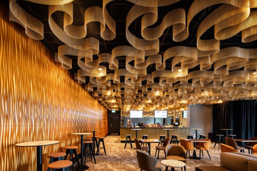 Photo of gold Kriskadecor decorative chains arranged in a wavy shapes on the ceiling of an elegant bar lounge