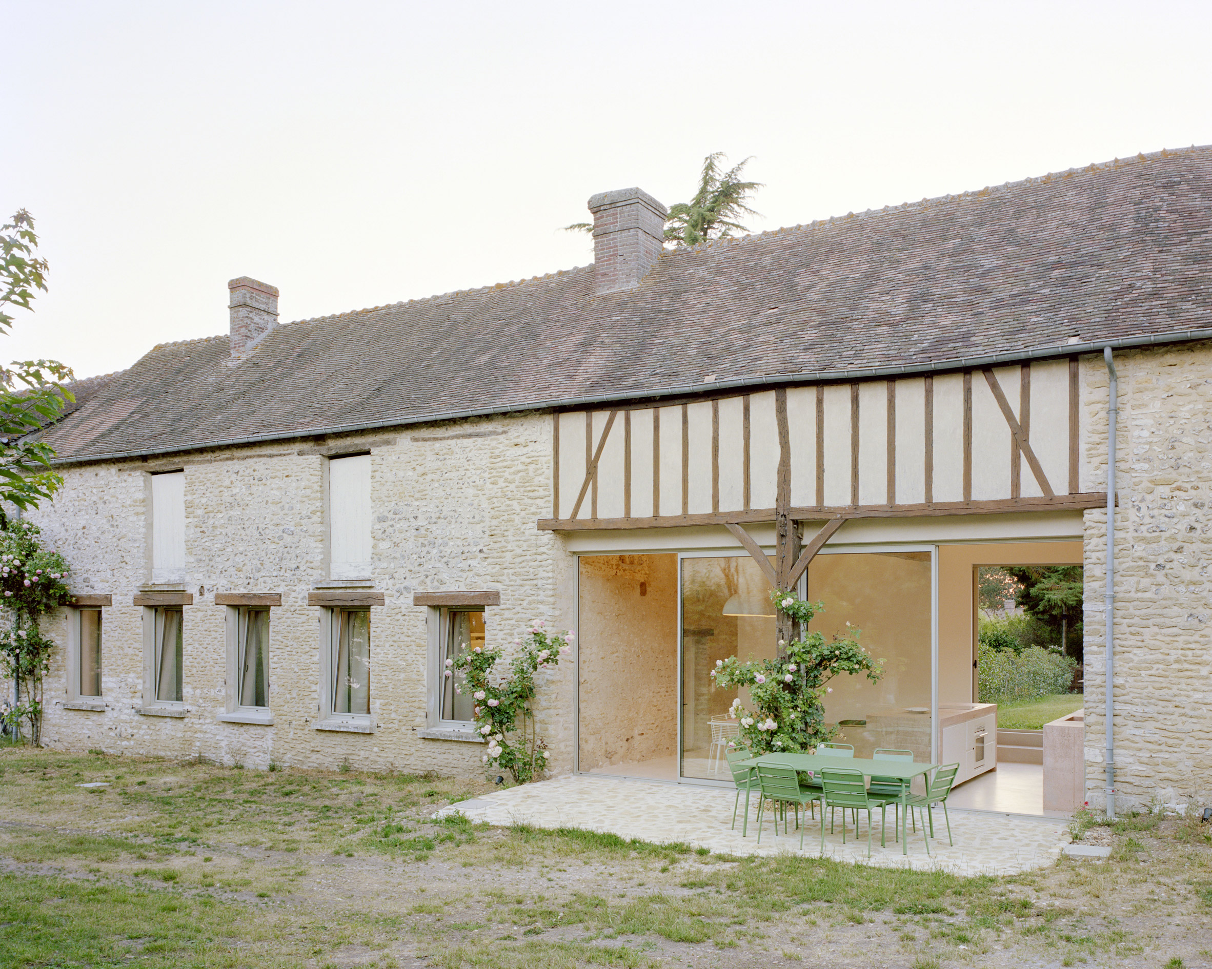 Exterior patio with stone paving at Maison Hercourt by Studio Guma in Normandy