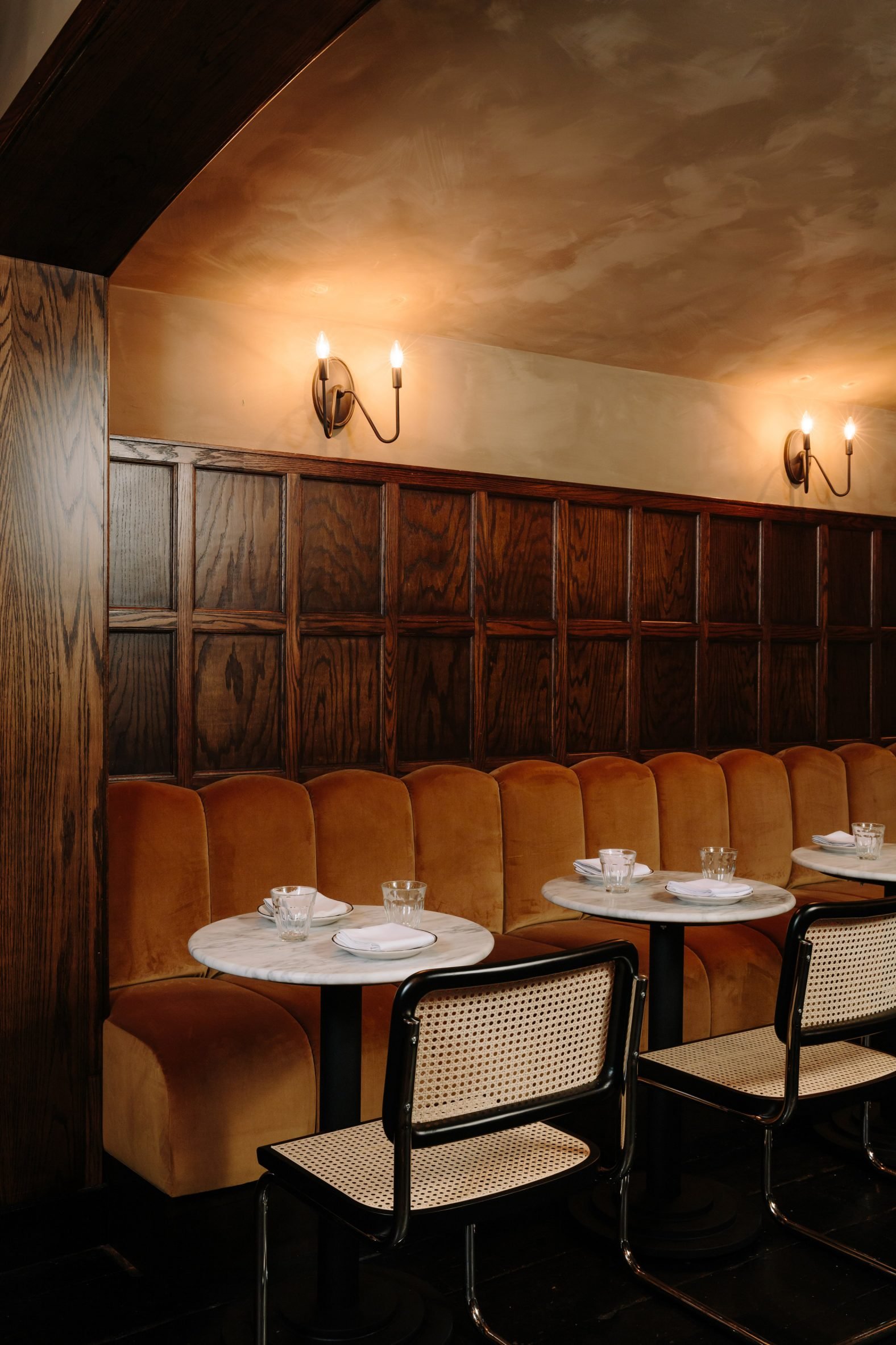 Banquette below walnut panelling and candle sconces