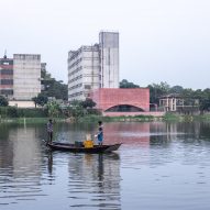 Two viewers in boats look across the water at Zebun Nessa Mosque by Studio Morphogenesis in Bangladesh
