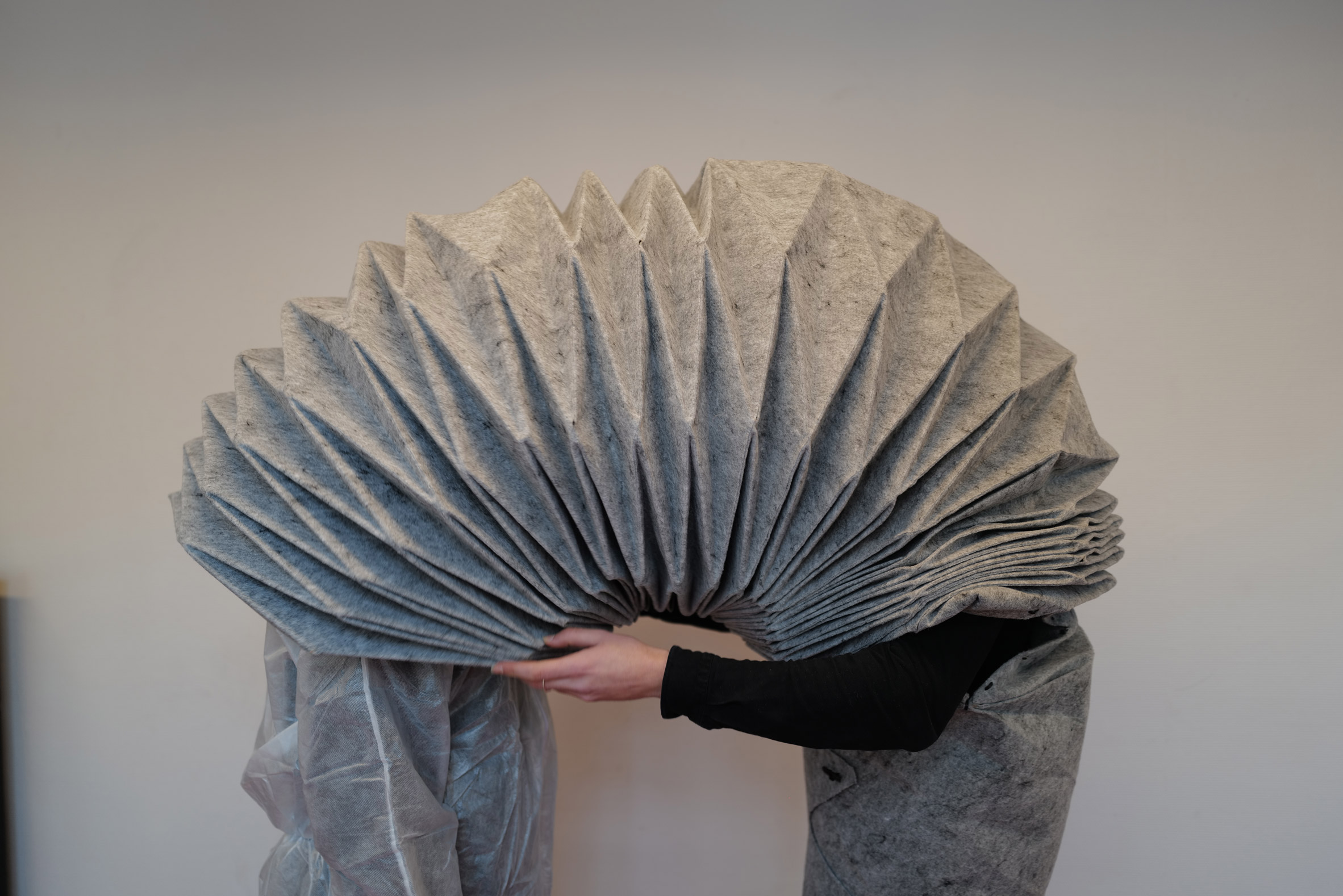 Photo of two people with their heads connected by a grey fabric tube