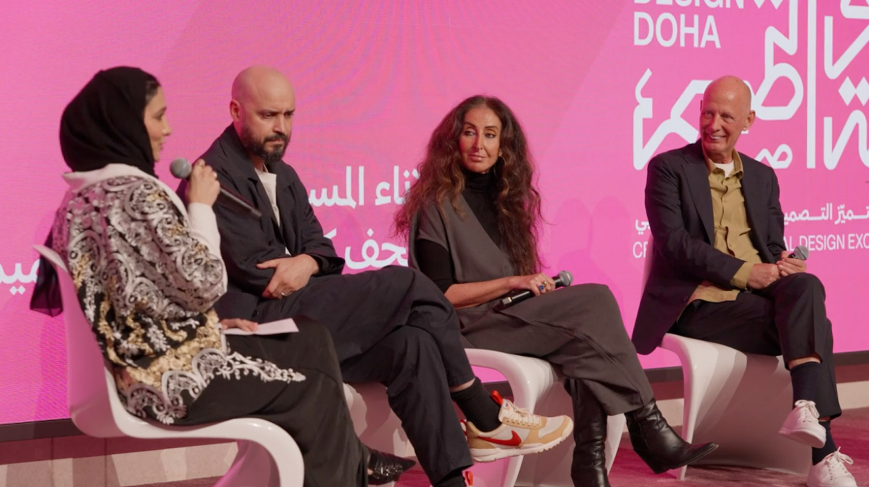 Video still of Samir Bantal, Manuela Lucà-Dazio and Ben van Berkel sitting on stage at a panel at the Design Doha Forum with a bright pink screen behind them