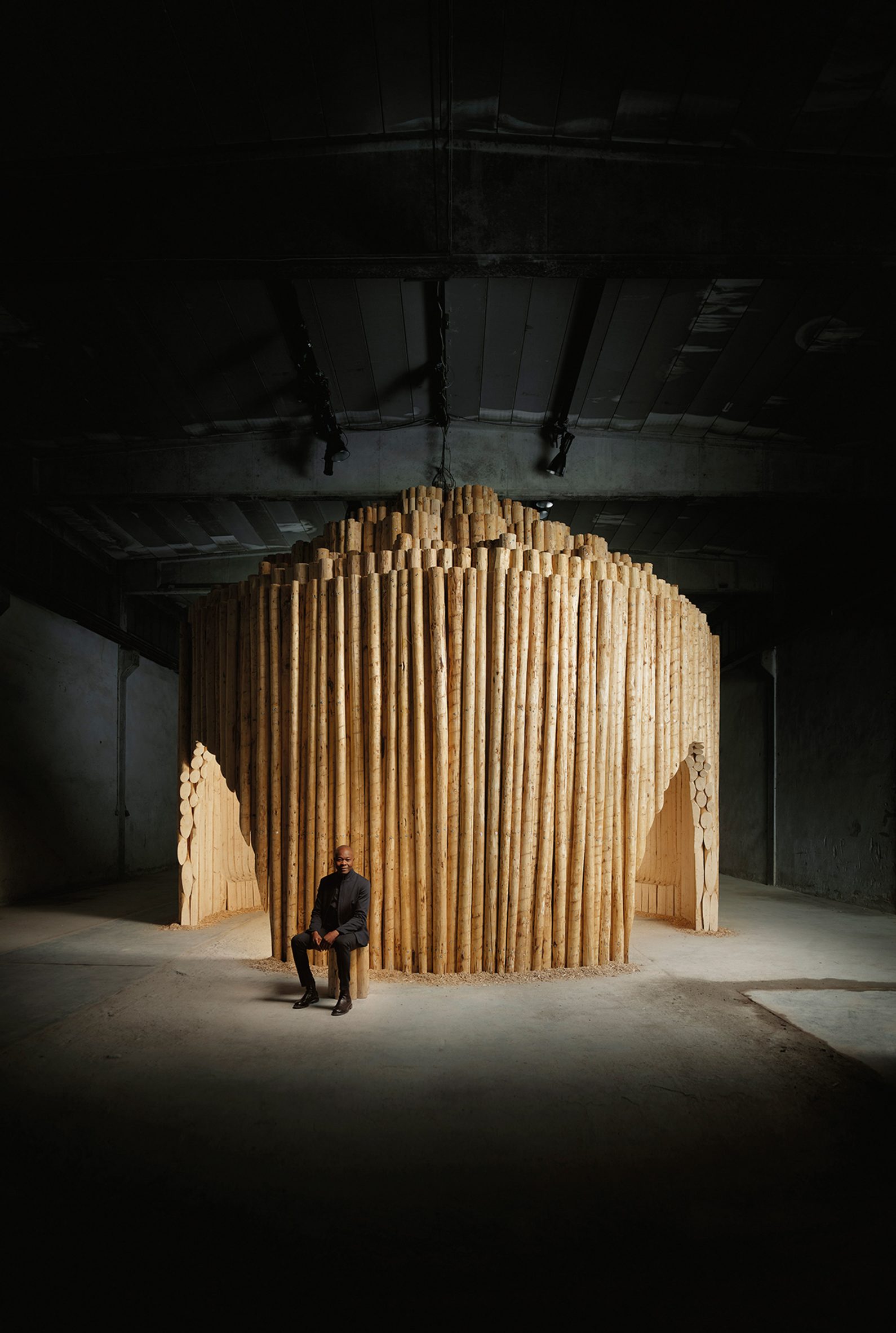 Diébédo Francis Kéré sat in front of wooden pavilion for Milan design week