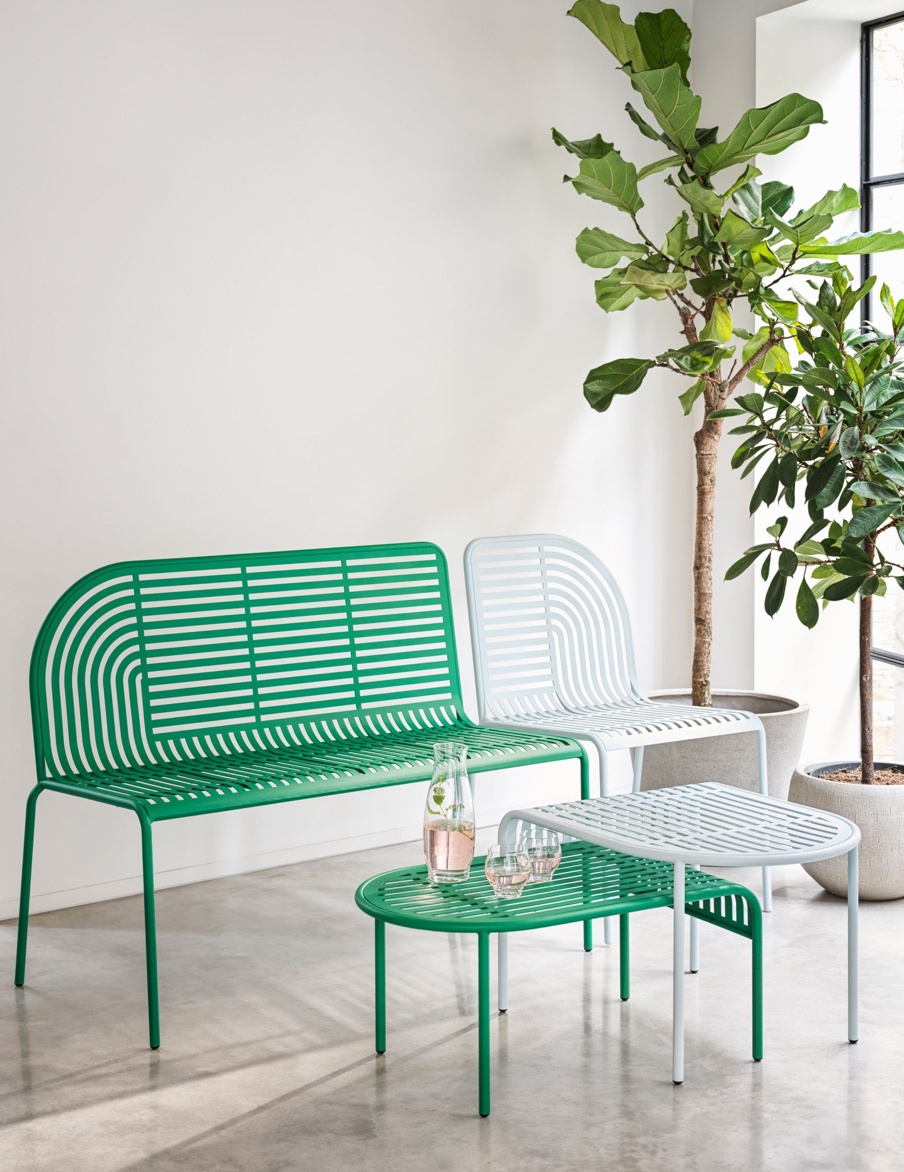 Lifestyle photo of Habitat's green and white outdoor chair, bench and nesting tables with plasma cut patterns