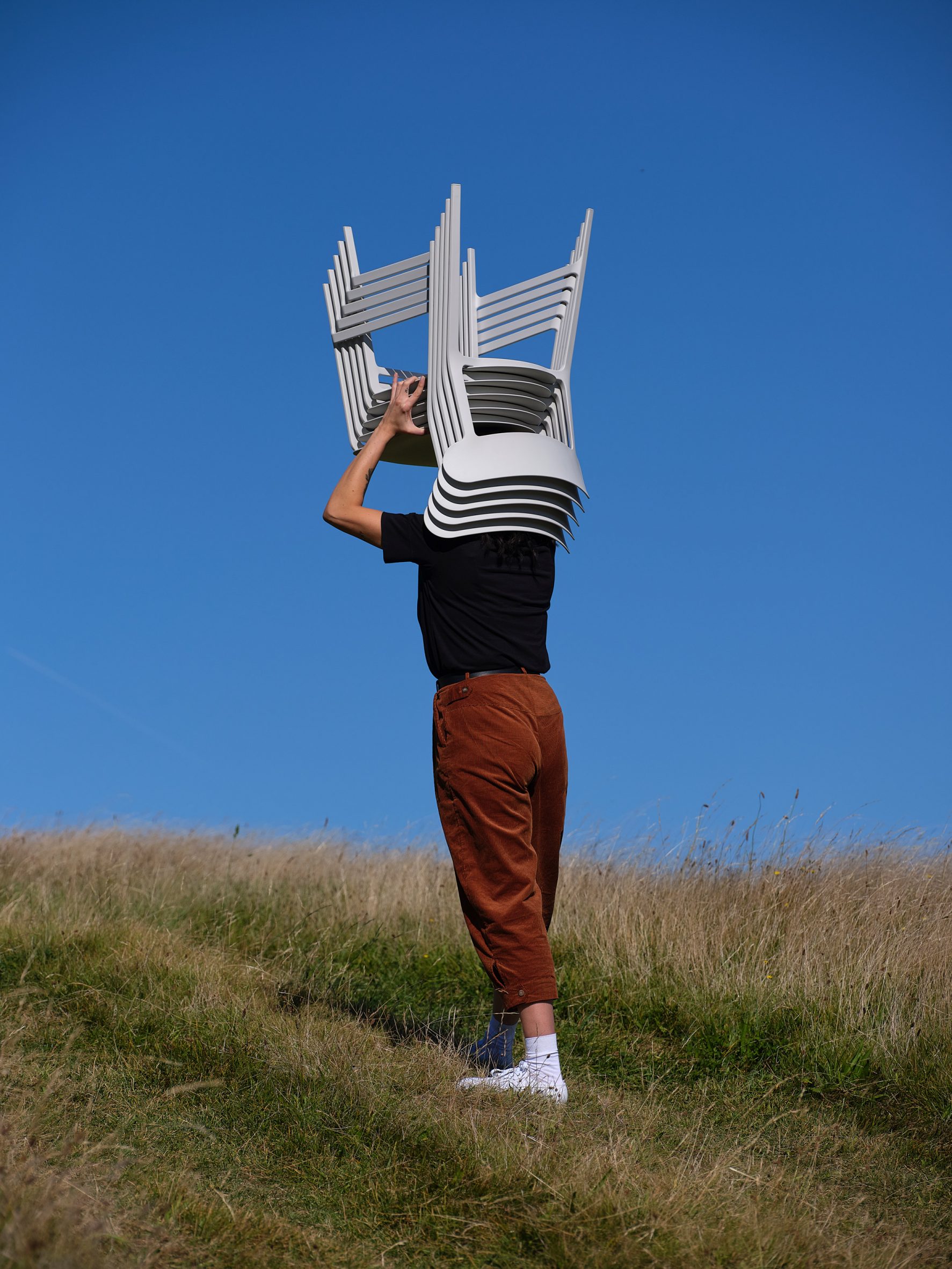 Person holding up a stack of chairs